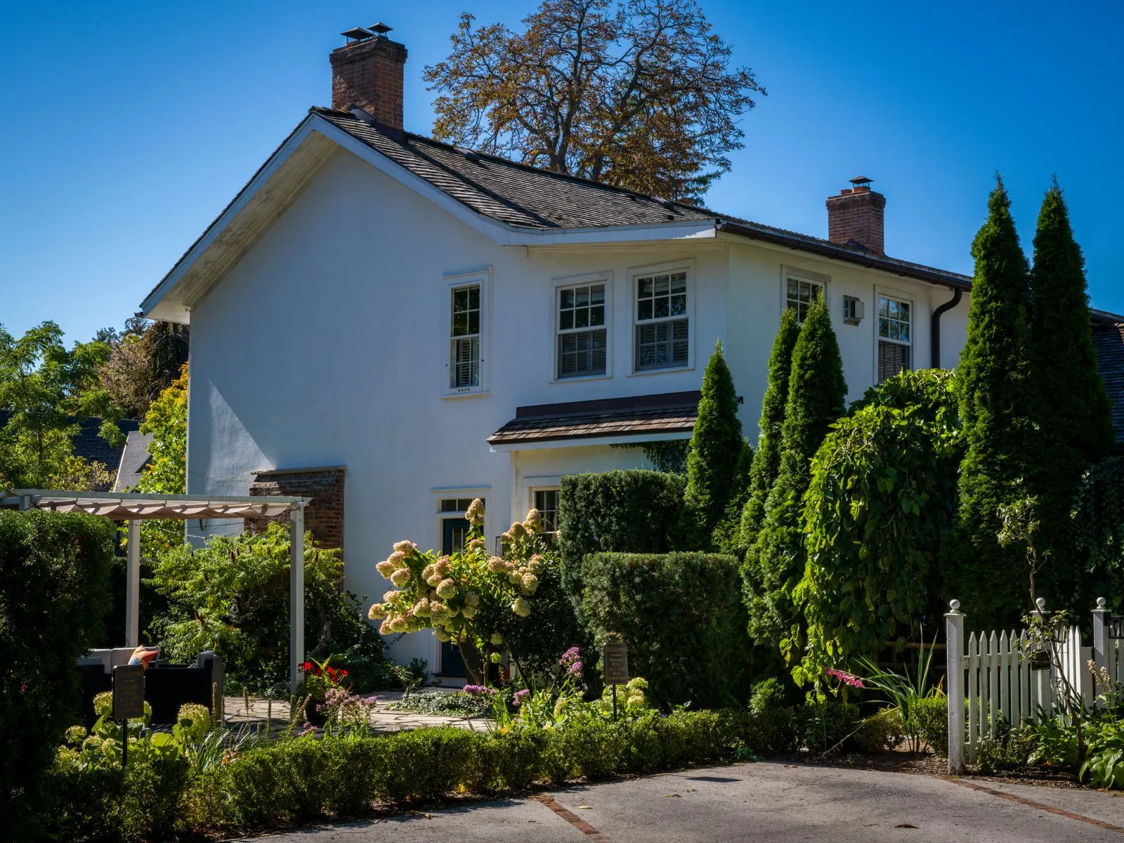 Beautiful suburban house surrounded by lush greenery and bright flowers in a serene setting.